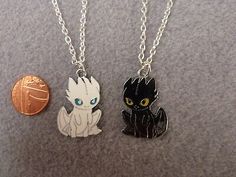 two necklaces with cats on them sitting next to a penny bank and a coin