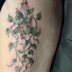 a close up of a person's leg with a tattoo on it and green leaves