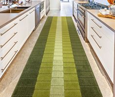 a kitchen with green and yellow rugs on the floor next to white cupboards