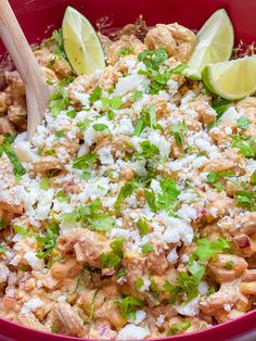 a red bowl filled with chicken and cilantro rice topped with lime wedges