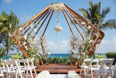 an outdoor ceremony setup with white chairs and flowers