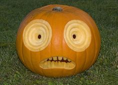 an orange pumpkin with googly eyes in the grass