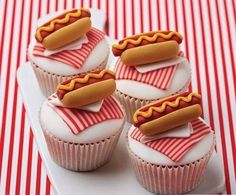 cupcakes with frosting and hot dogs on them are sitting on a plate