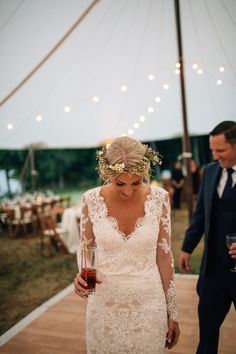 a bride and groom walking down the aisle at their outdoor wedding reception with string lights in the background