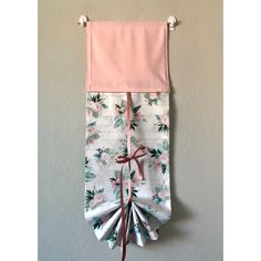 a pink and white towel hanging on the wall with ribbons attached to it's sides