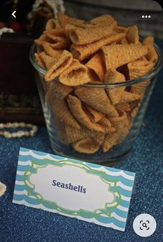 a glass bowl filled with cheetos sitting on top of a blue table cloth