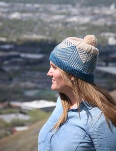 a woman with long hair wearing a knitted hat and looking out over the city