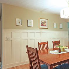 a dining room table and chairs with pictures on the wall