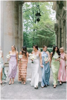 a group of women standing next to each other in long dresses and holding bouquets