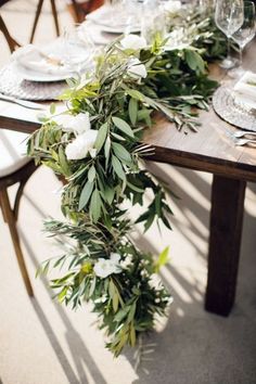 the table is set with white flowers and greenery