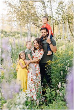 a man and two children are posing for a family photo in the wildflowers