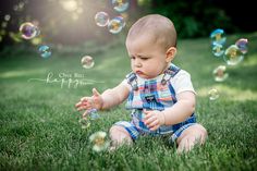 a baby sitting in the grass playing with bubbles