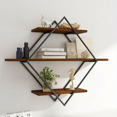 three shelves with books, vases and other items on them against a white wall