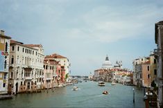 the boats are traveling down the river in the city center, with many buildings on both sides