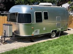 an airstream is parked next to a wooden fence