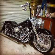 a black motorcycle parked in front of a garage door with chrome rims on it