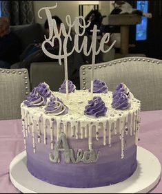 a purple and white cake with icing that says suitee on top, sitting on a table