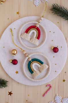 two christmas ornaments are sitting on a white plate next to fir branches and decorations that include candy canes