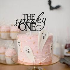 there is a pink cake with white frosting and spooky ghost decorations on it