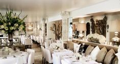 a dining room with tables and chairs covered in white linens, decorated with flowers