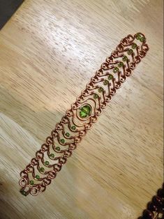 a bracelet with green stones on it sitting on a table