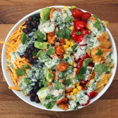 a large bowl filled with taco salad on top of a wooden table