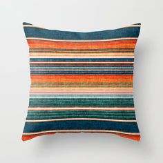 a multicolored striped pillow on a white wall with a black and orange background