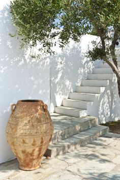 a large vase sitting on the ground next to a tree and steps leading up to it