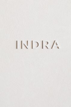 the word indra spelled in cut out letters on a white wall with no one around it