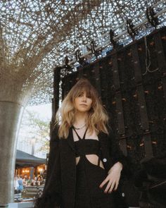 a woman standing in front of a building with lots of lights hanging from the ceiling