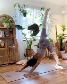 a woman is doing yoga in her living room with plants on the wall behind her