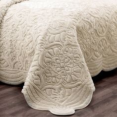 a bed with a white bedspread on top of it next to a wooden floor