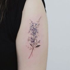 a woman's arm with a small flower tattoo on the left side of her arm