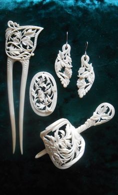 four pieces of carved ivory jewelry on a velvet surface