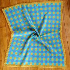 a blue and yellow blanket laying on top of a wooden floor