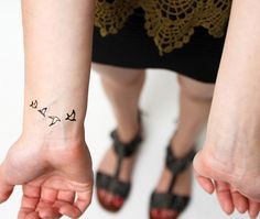 a small tattoo on the wrist of a woman with an anchor and cross in it