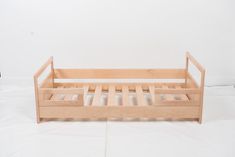 a wooden bed frame sitting on top of a white sheet covered floor next to a wall