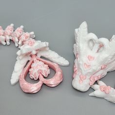 two pink and white figurines sitting next to each other on a gray surface