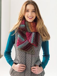 a woman wearing a knitted scarf and smiling at the camera with her hands on her hips