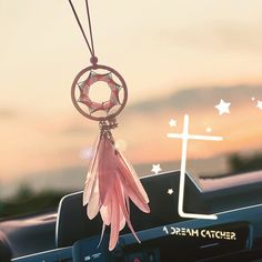 a pink dream catcher hanging from the dashboard of a car