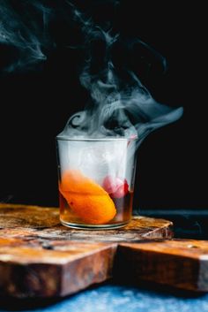 a glass filled with liquid sitting on top of a wooden cutting board