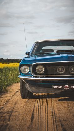 the front end of a blue car on a dirt road