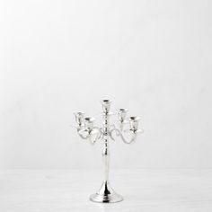 a silver candelabra with five candles on it sitting on a white table