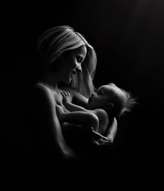 a woman holding a baby in her arms with the light shining on her face behind her