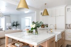 a kitchen with marble counter tops and gold pendant lights