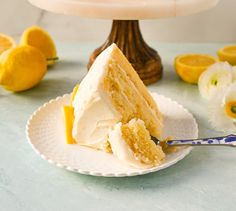 a slice of cake on a plate with lemons and flowers in the back ground