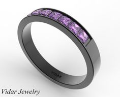 a black gold ring with purple stones in the center and an inscription that reads vivar jewelry