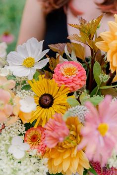 a woman holding a bouquet of flowers in her hands