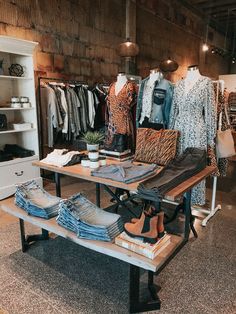 a table topped with lots of clothes and shoes next to a shelf filled with shirts