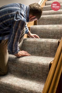 a man is climbing up the stairs with his hand on the carpet and looking down